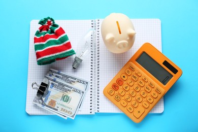 Photo of Flat lay composition with piggy bank and calculator on light blue background. Paying bills concept