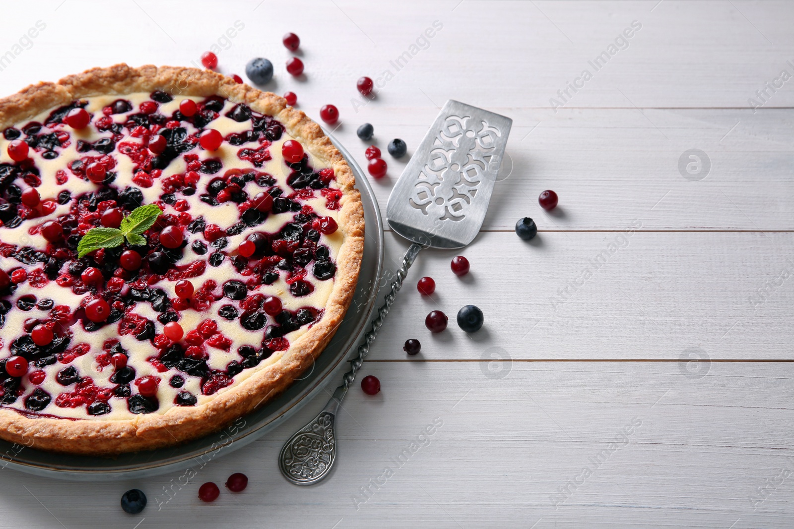 Photo of Delicious currant pie and fresh berries on white wooden table, space for text