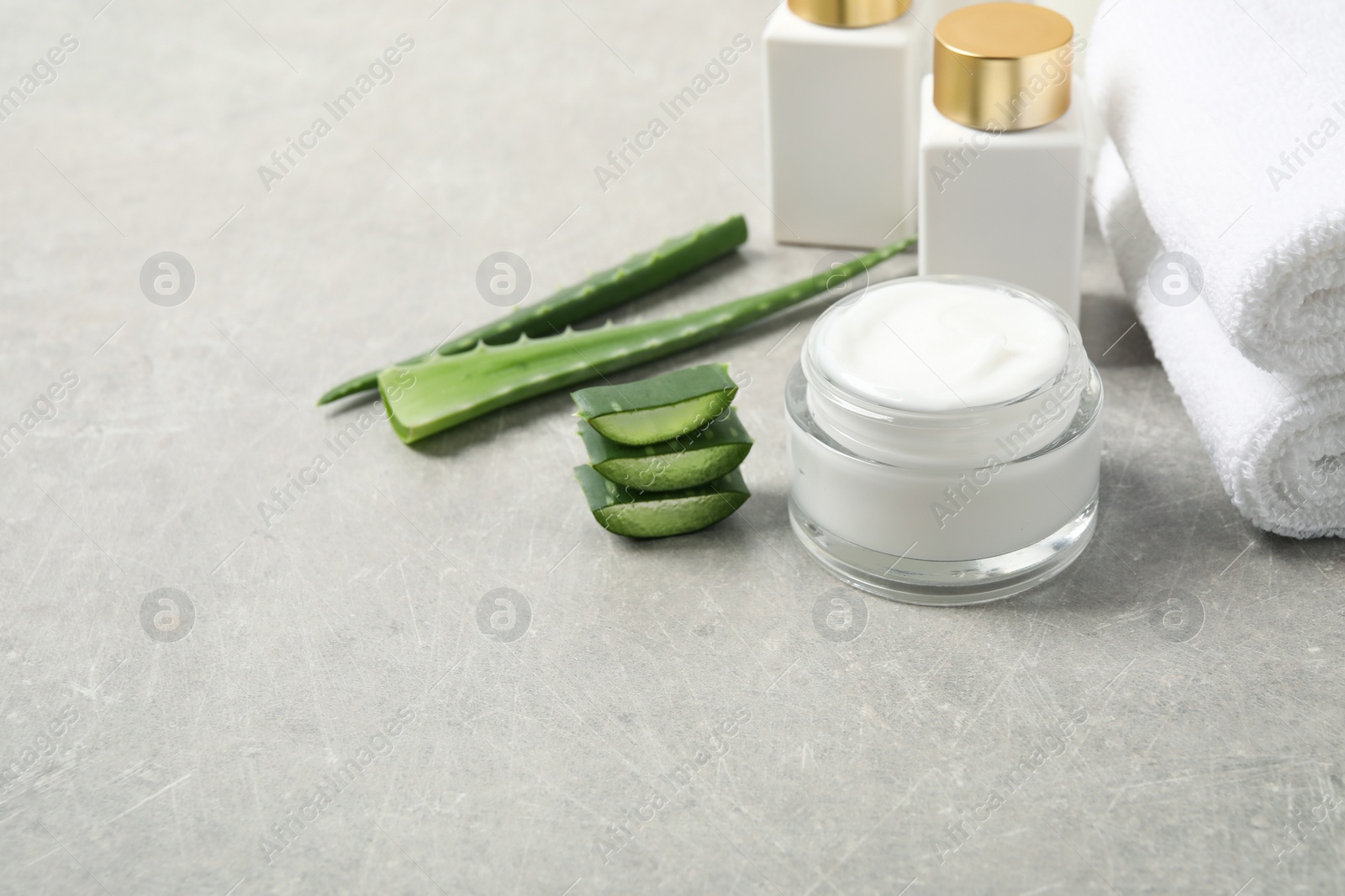 Photo of Different cosmetic products, towels and aloe on grey table