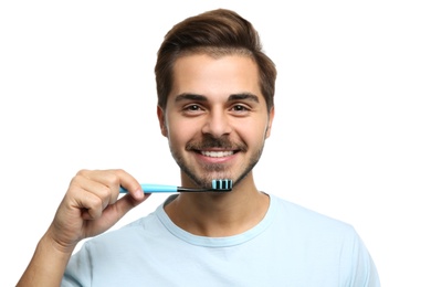 Portrait of young man with toothbrush on white background