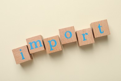 Photo of Word Import made of wooden cubes with letters on beige background, flat lay