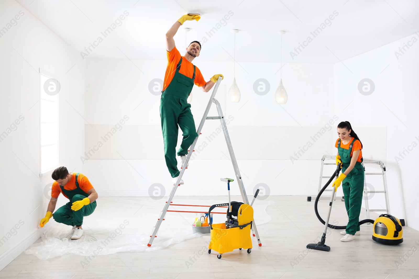 Photo of Team of professional janitors cleaning room after renovation