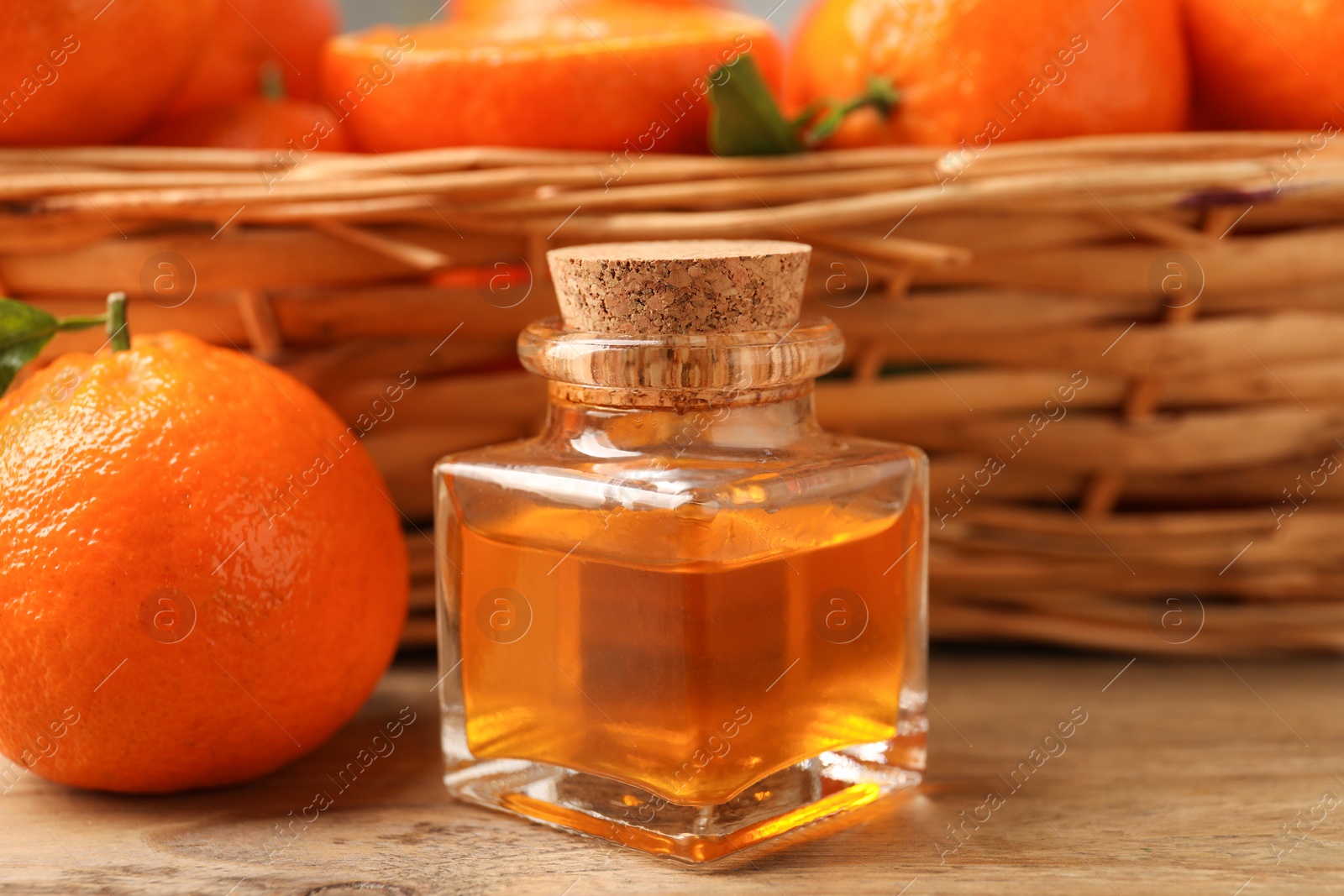 Photo of Bottle of tangerine essential oil and fresh fruits on wooden table, closeup