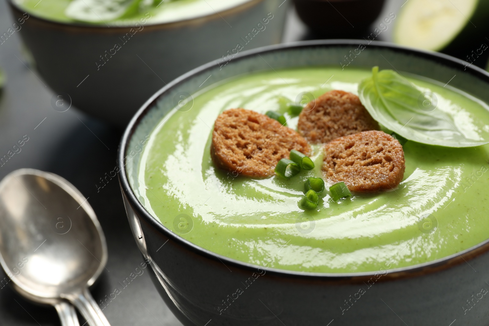 Photo of Tasty homemade zucchini cream soup in bowl, closeup