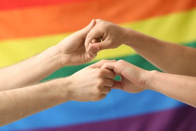 Photo of Gay couple holding hands on rainbow background