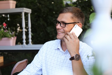 Photo of Businessman talking on smartphone in outdoor cafe