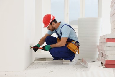 Photo of Electrician with screwdriver repairing power socket indoors