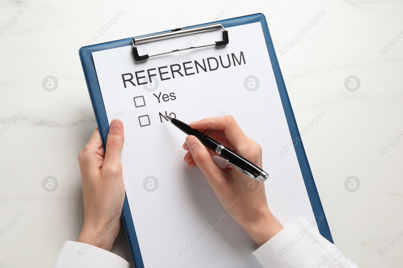 Photo of Woman with referendum ballot making decision at white marble table, closeup