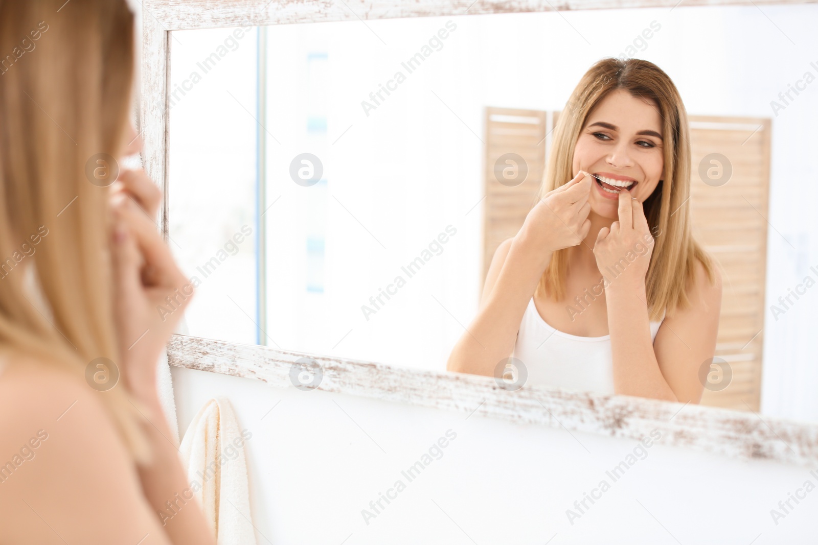 Photo of Young woman flossing her teeth in bathroom