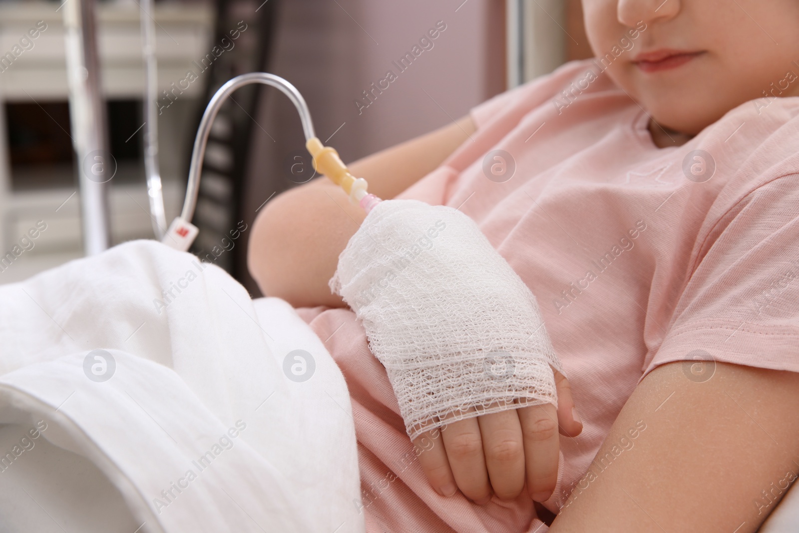 Photo of Little child with intravenous drip in hospital bed, closeup