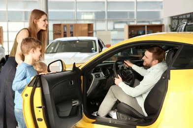 Photo of Young family choosing new car in salon