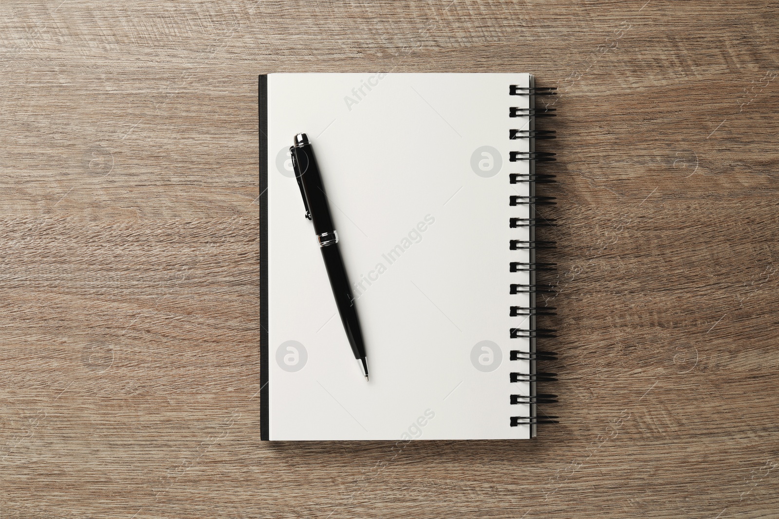 Photo of Notebook and pen on wooden table, top view