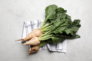 Photo of Fresh sugar beets with leaves on light grey table, flat lay