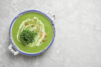 Photo of Tasty kale soup with pumpkin seeds on light grey marble table, top view. Space for text