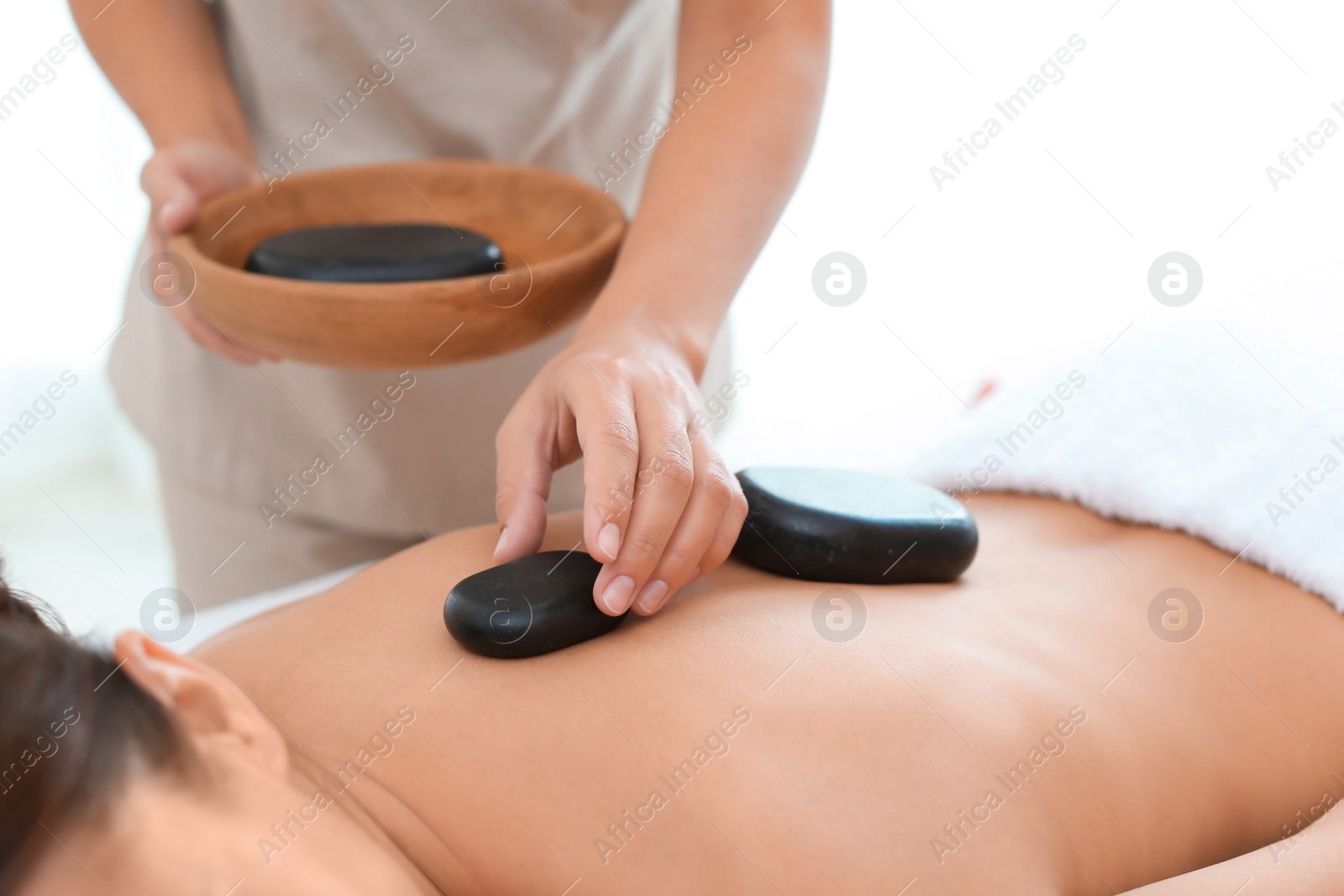 Photo of Beautiful young woman getting hot stone massage in spa salon