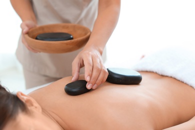 Photo of Beautiful young woman getting hot stone massage in spa salon