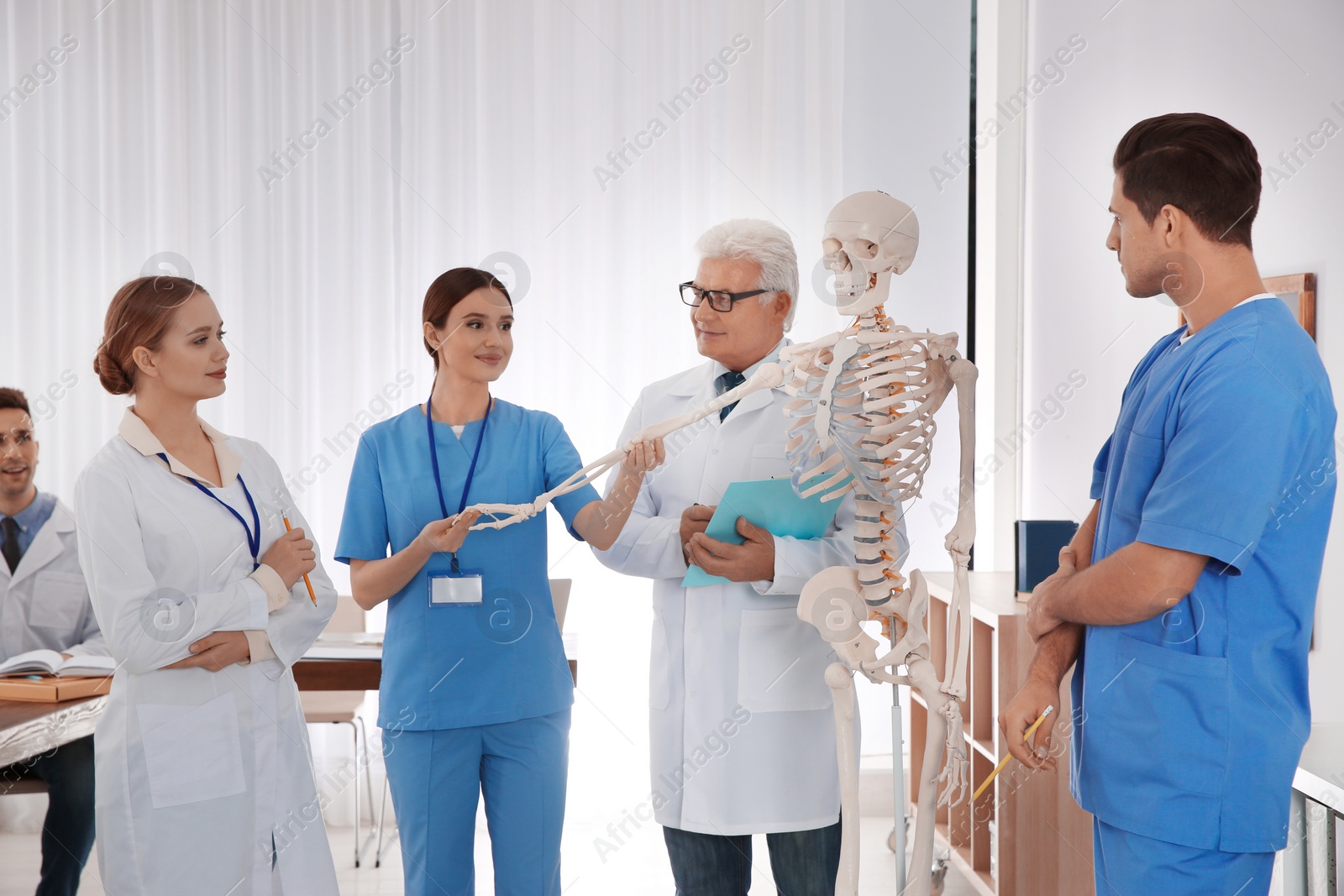 Photo of Medical students and professor studying human skeleton anatomy in classroom