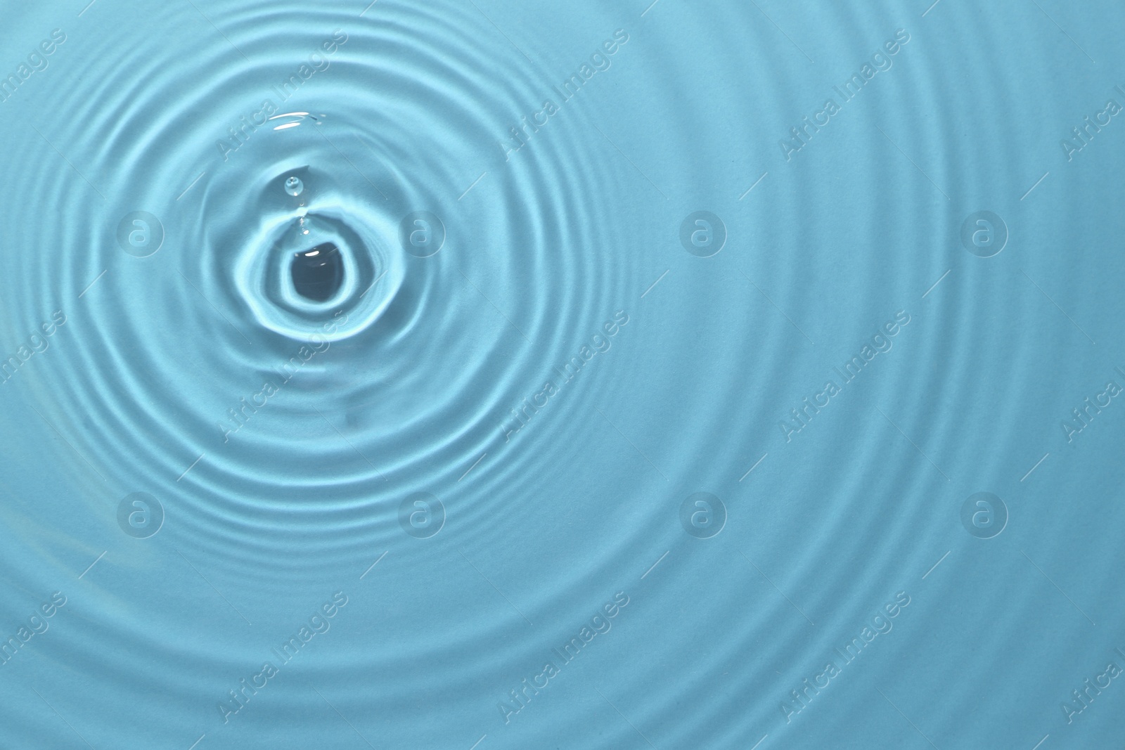 Image of Rippled surface of clear water on light blue background, top view