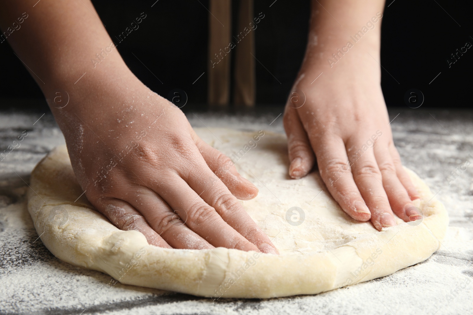 Photo of Woman kneading dough for pizza at grey table, closeup