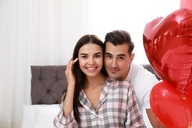 Photo of Beautiful couple with heart shaped balloons in bedroom