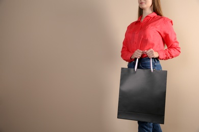Photo of Woman holding paper shopping bag on color background. Mock up for design