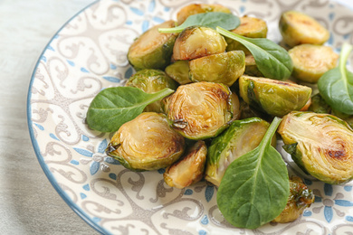 Photo of Delicious roasted brussels sprouts with basil on plate, closeup