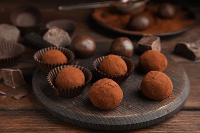 Photo of Delicious chocolate truffles powdered with cocoa on wooden table