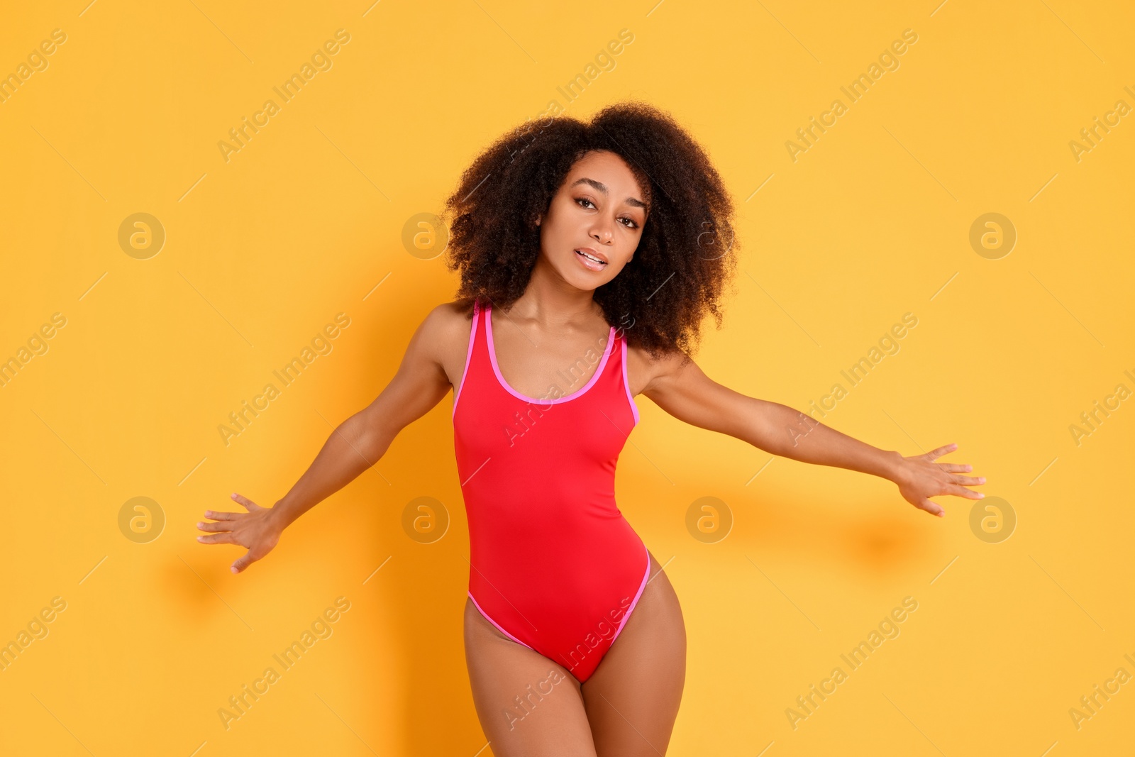 Photo of Beautiful woman in bright one-piece summer swimsuit on yellow background