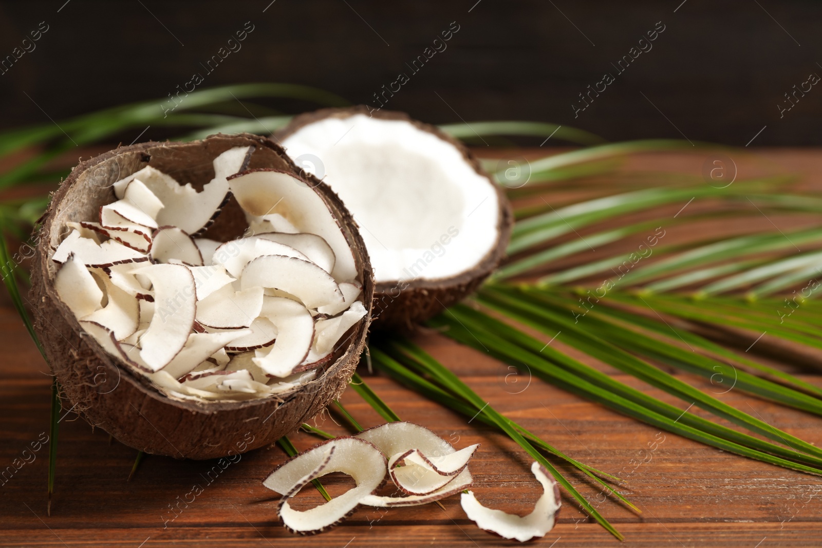Photo of Tasty coconut chips on wooden table. Space for text