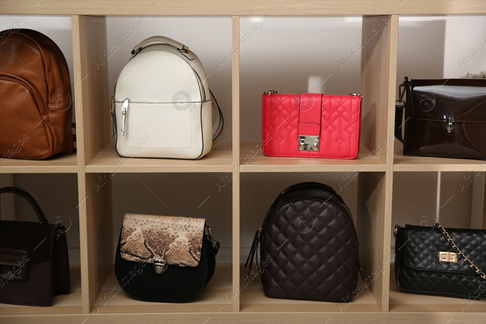 Photo of Collection of stylish woman's bags on wooden shelving unit