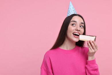 Woman in party hat eating piece of tasty cake on pink background, space for text