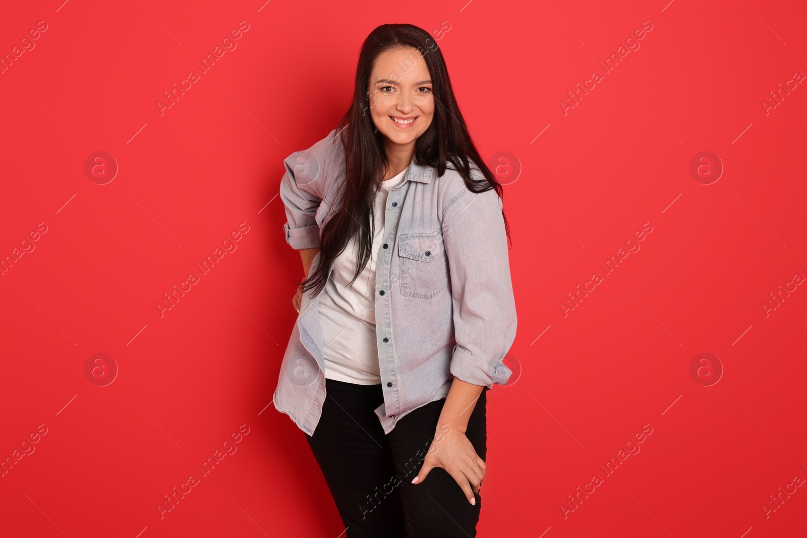 Photo of Beautiful overweight woman with charming smile on red background