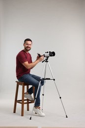 Photo of Smiling astronomer with telescope on light grey background