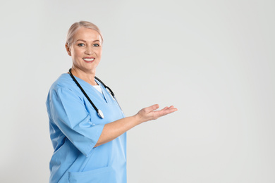 Photo of Portrait of mature doctor with stethoscope on light grey background. Space for text