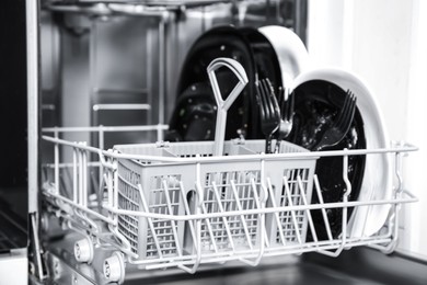 Photo of Open dishwasher with dirty tableware in kitchen, closeup