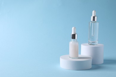 Photo of Presentation of bottles with cosmetic serums on light blue background, space for text