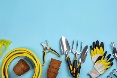 Flat lay composition with gardening tools on light blue background, space for text