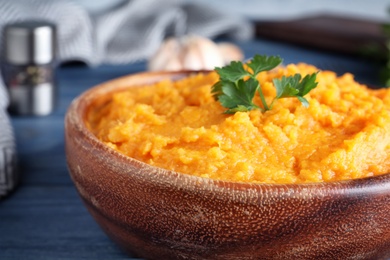 Photo of Bowl with mashed sweet potatoes on wooden table, closeup