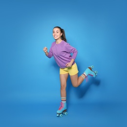 Young woman with roller skates on color background