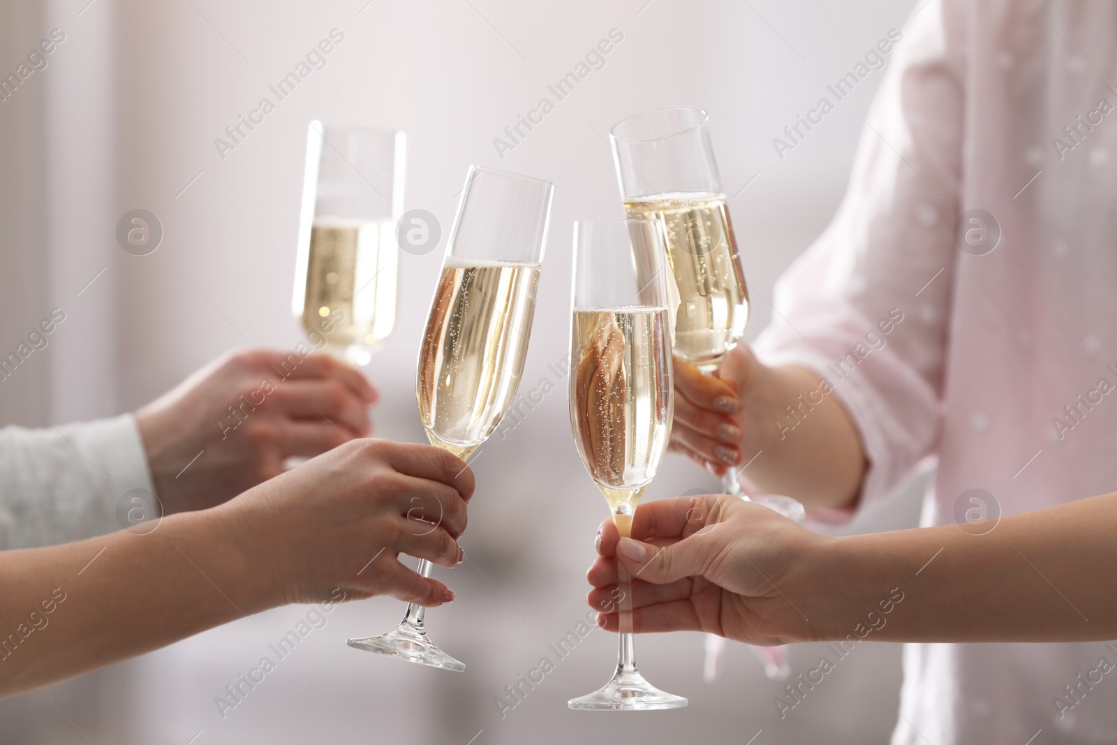 Photo of People clinking glasses of champagne against blurred background, closeup