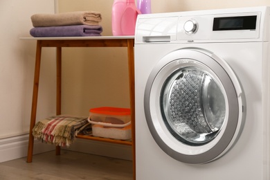 Photo of Modern white washing machine in laundry room