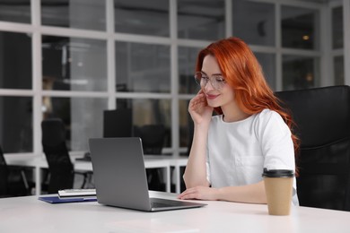 Happy woman working with laptop at white desk in office