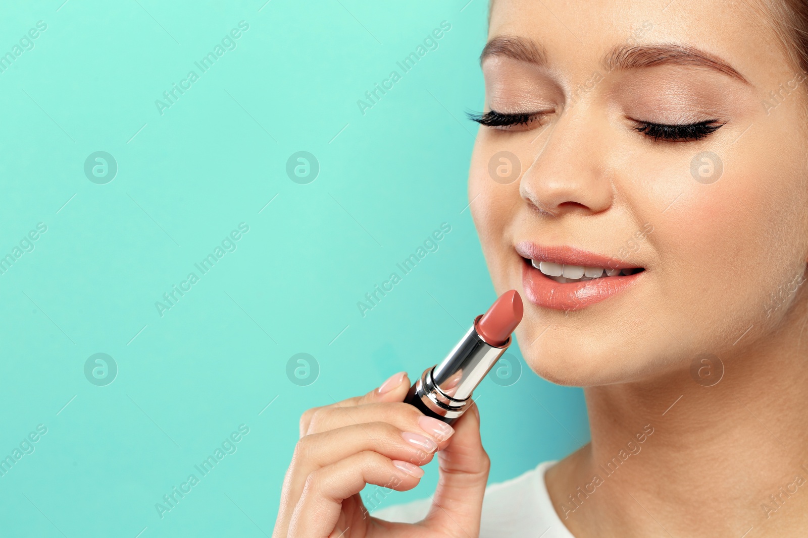 Photo of Beautiful woman applying nude lipstick on color background. Space for text