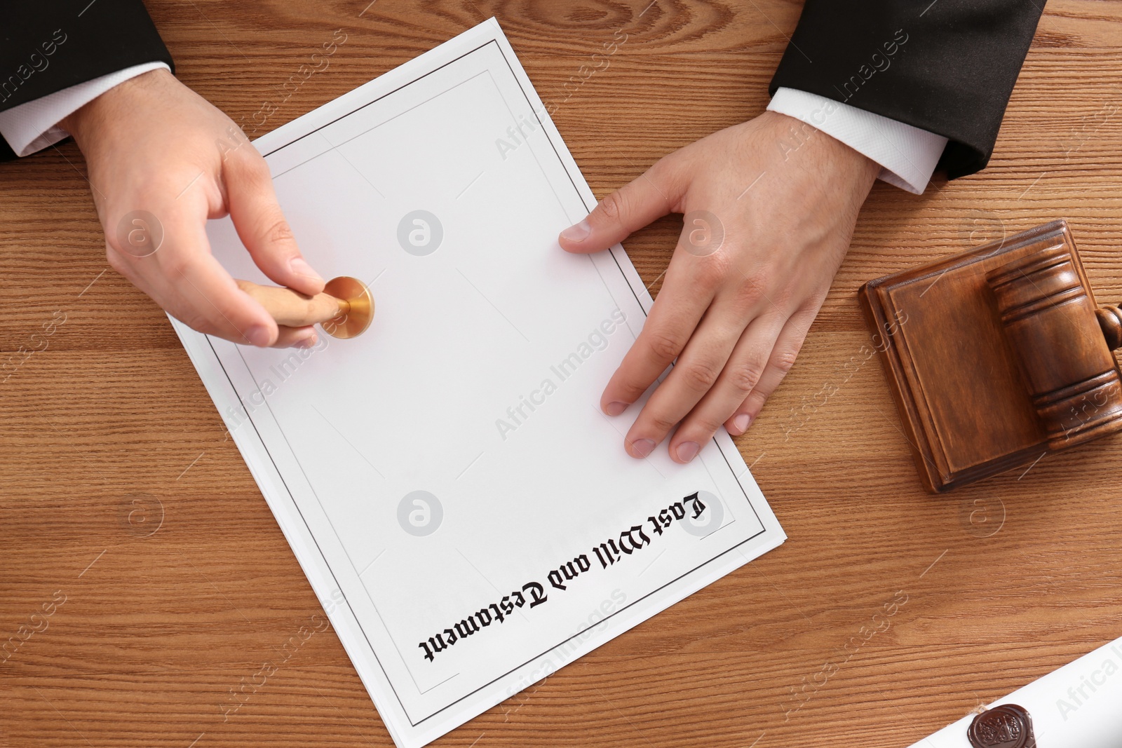 Photo of Male notary stamping document at wooden table, top view