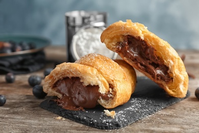 Photo of Tasty croissant with chocolate on wooden table