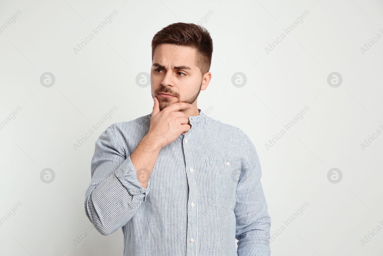 Photo of Pensive man on light background. Thinking about answer for question