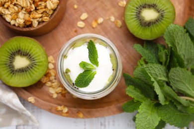 Delicious dessert with kiwi, yogurt and mint on wooden board, flat lay