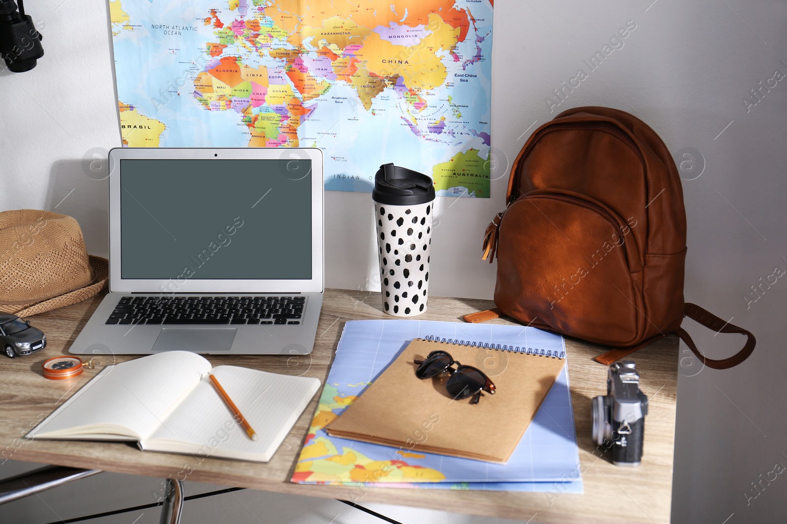 Photo of Laptop, notebook and travel accessories on wooden table. Planning summer vacation trip