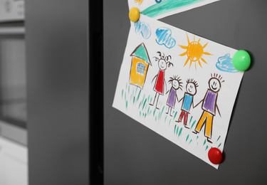 Modern refrigerator with child's drawing and magnets