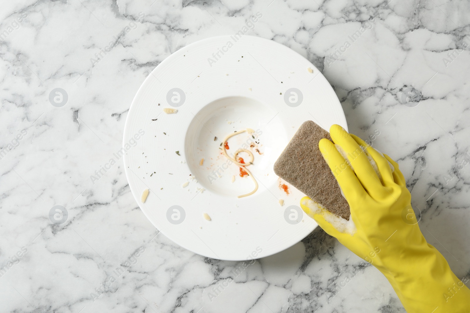 Photo of Woman washing dirty plate at white marble table, top view